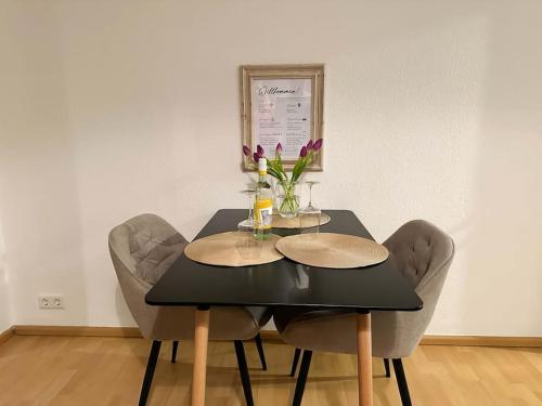 a black dining table with chairs and flowers on it at Gemütliche 2-Zimmer Wohnung im Zentrum in Neumünster