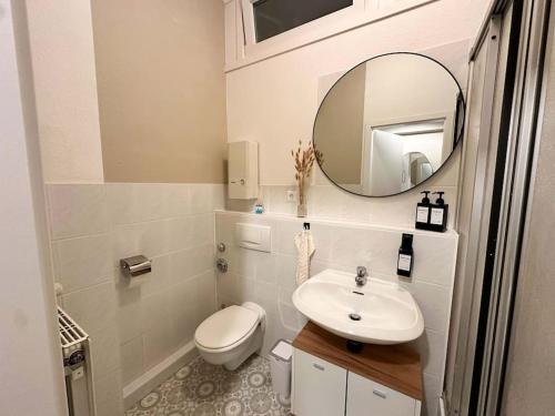 een badkamer met een wastafel, een toilet en een spiegel bij Gemütliche 2-Zimmer Wohnung im Zentrum in Neumünster