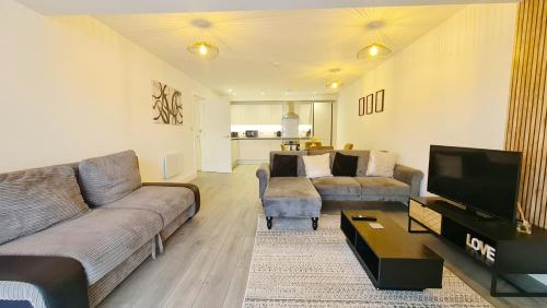 a living room with a couch and a tv at Premium CITY APARTMENT near Harry Potter Studio and Luton Airport in Hemel Hempstead