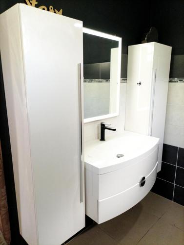 uma casa de banho branca com um lavatório e um espelho em Villa orchidée em Les Abymes