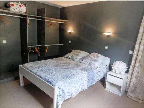 um pequeno quarto com uma cama com lençóis azuis e brancos em Villa orchidée em Les Abymes