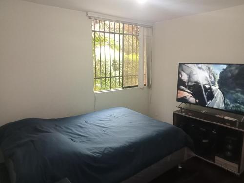 a bedroom with a bed and a flat screen tv at Acogedora Habitacion Independiente in Lima