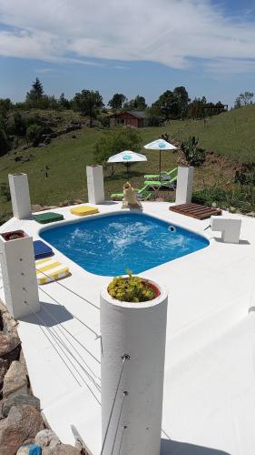 a swimming pool with chairs and umbrellas next to it at Cabañas & Suites "No es Fácil" in Villa Yacanto