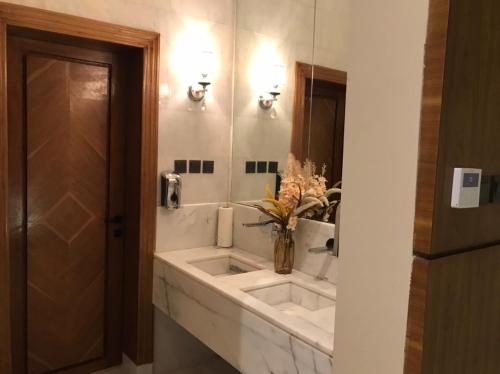 un baño con lavabo y un jarrón con flores. en SAAF RESORT en Al Ghuţghuţ