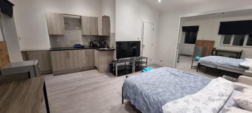 ein Wohnzimmer mit zwei Betten und eine Küche in der Unterkunft Ilford Towncentre Large Studio in Ilford