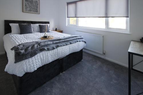 een slaapkamer met een groot bed en een raam bij Contractors, Medical staff, Relocators, Families- 5 Bedroom 3 bathroom house- 2min walk to L&D in Luton