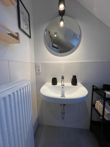 a bathroom with a white sink and a mirror at Sonnige Dachwohnung nahe dem Klinikum. in Oldenburg