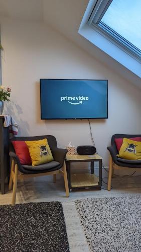 a living room with two chairs and a tv on the wall at Sidney Grove B&B in Newcastle upon Tyne