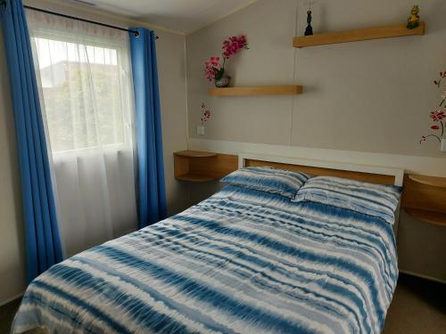 a bedroom with a bed and a window with blue curtains at 205 Holiday Resort Unity Pet friendly 6 berth passes included in Brean