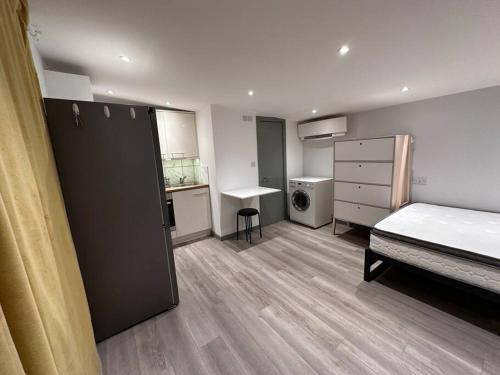 een kleine kamer met een bed en een keuken bij Cosy, self-contained guest house in Thornton Heath