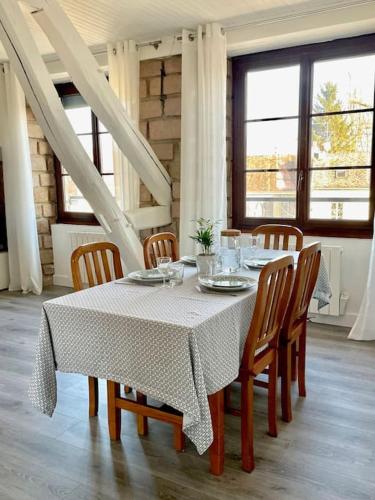 une table à manger avec des chaises et un tissu de table blanc dans l'établissement Appartement centre ville Milly-la-Forêt, à Milly-la-Forêt