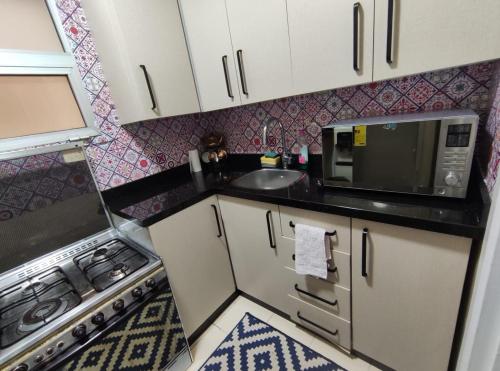 a small kitchen with a sink and a microwave at Madinty amazing view 2 rooms fully air-conditioned apartment at Madinty city for families only مدينتي in Madinaty