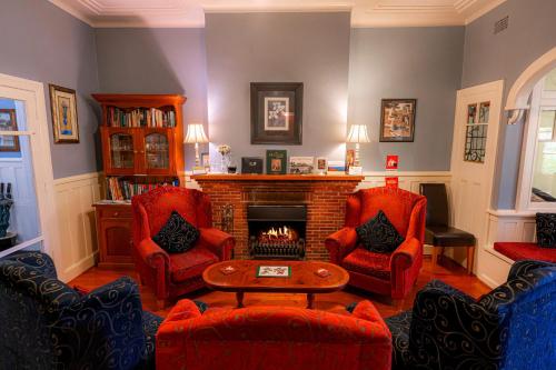 a living room with red chairs and a fireplace at KUBBA ROONGA GUESTHOUSE - Boutique Luxury Peaceful Stay & Gardens - Bed & Breakfast in Blackheath