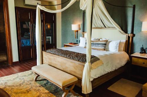 a bedroom with a canopy bed and a chair at Casa Raíces Hotel Luxury & Viñedo in Los Galvanes