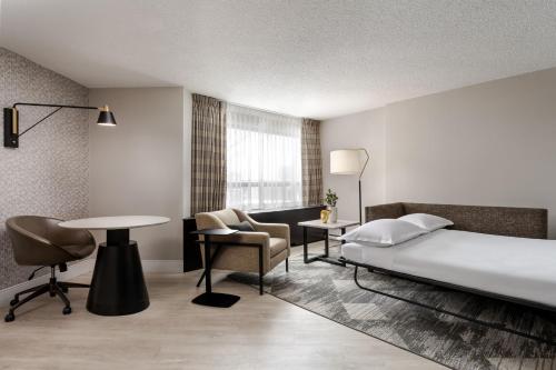 Sheraton Montreal Airport Hotel في دورفال: غرفة في الفندق بسرير ومكتب وطاولة