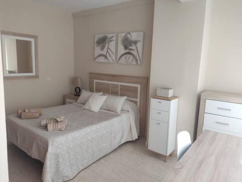 a white bedroom with a bed and a dresser at Acogedor Apartamento frente al mar Elena y Michele in Almería