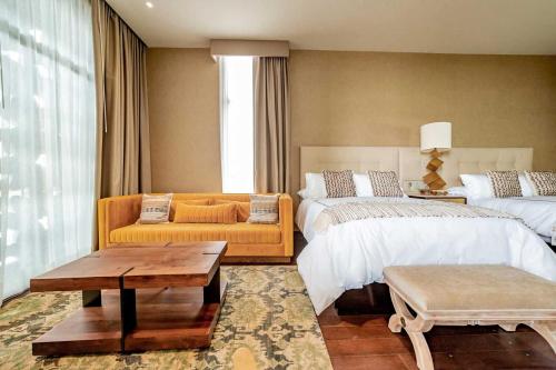 a living room with two beds and a couch at Casa Raíces Hotel Luxury & Viñedo in Los Galvanes