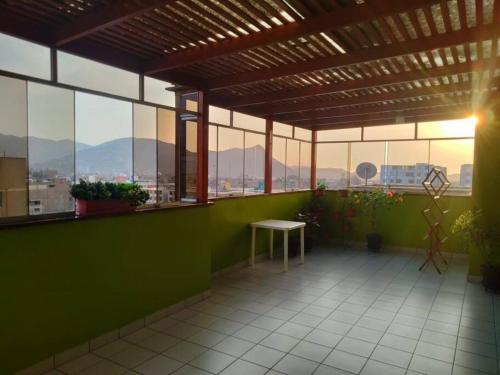 uma sala verde com uma mesa e algumas janelas em Tait's House - Cómodo departamento Dúplex - Ate em Lima