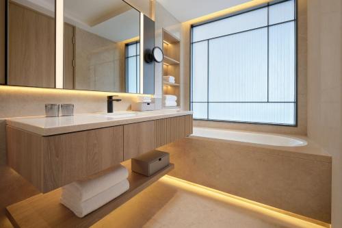 a bathroom with a sink and a mirror and a tub at Courtyard By Marriott Shanghai Xujiahui in Shanghai