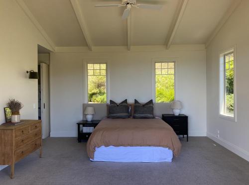 a bedroom with a bed with two tables and two windows at Ocean Beach in Tuki Tuki