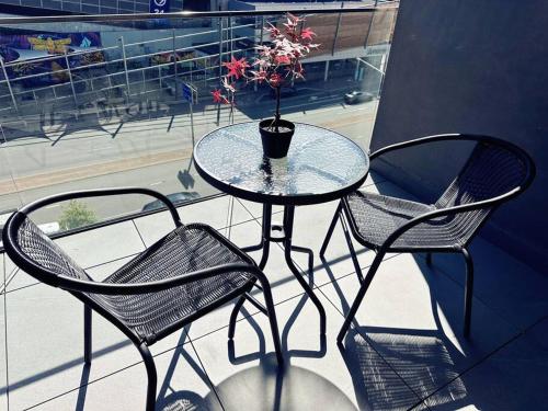 a glass table with two chairs and a vase with flowers at Lovely City 1BR Apt Free Parking & Facing Mall in Canberra