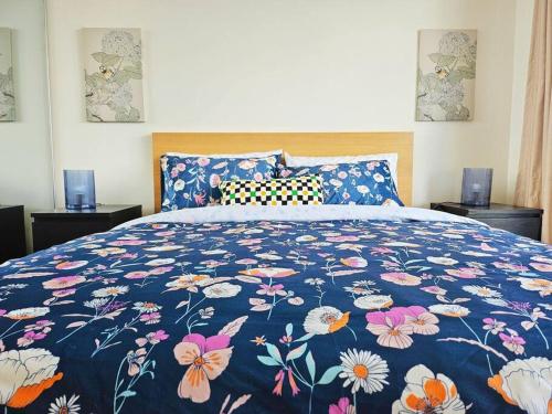 a bed with a blue floral bedspread with flowers on it at Lovely City 1BR Apt Free Parking & Facing Mall in Canberra