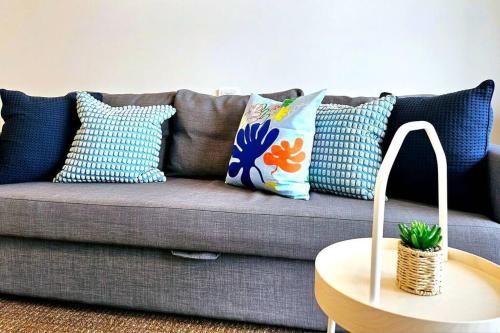 a couch with pillows and a table in a living room at Lovely City 1BR Apt Free Parking & Facing Mall in Canberra