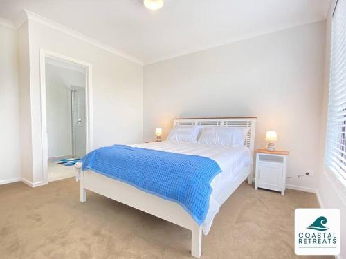 a white bedroom with a large bed and a window at Scotty’s Place – Luxury Retreat in Inverloch