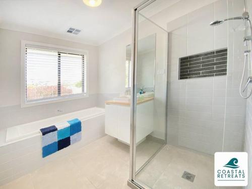 a bathroom with a glass shower and a sink at Scotty’s Place – Luxury Retreat in Inverloch