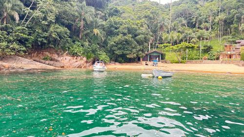 two boats sitting in the water near a beach at Jardim das Palmeiras II Home Resort in Ubatuba