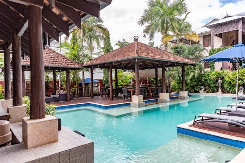 een zwembad met een prieel en een resort bij Hibiscus Resort & Spa with Onsite Reception & Check In in Port Douglas