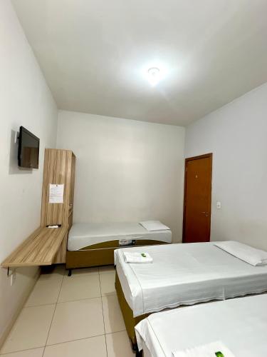 a small room with two beds and a tv at Kitnet Realeza in Várzea Grande