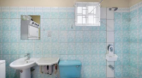 a blue tiled bathroom with a sink and a toilet at Cosy 1 Bd-Rm is steps away from Beach access. in Morne Rouge