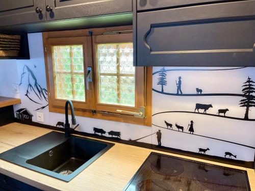 eine Küche mit einem Waschbecken und an der Wand bemalte Tiere in der Unterkunft Gstaad Chalet in Gstaad