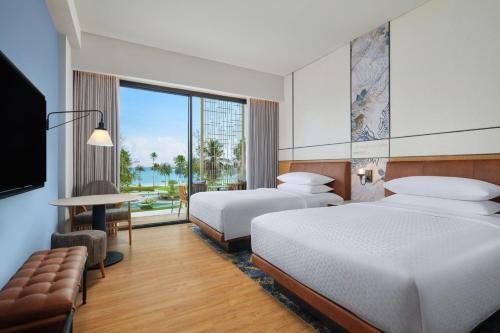 a hotel room with two beds and a television at Four Points by Sheraton Bintan, Lagoi Bay in Lagoi