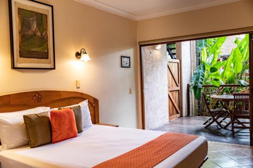 a bedroom with a bed and a balcony with a table at Hibiscus Resort & Spa with Onsite Reception & Check In in Port Douglas