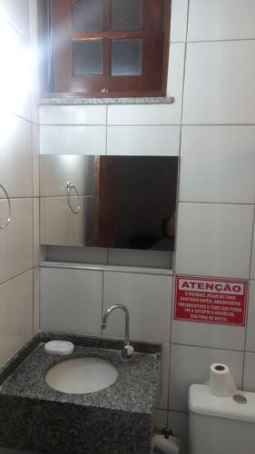 a bathroom with a sink and a mirror and a toilet at Sítio Guaramiranga para 10 pessoas com fácil acesso in Guaramiranga