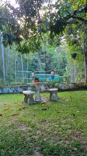 two people sitting at a picnic table in a park at Sítio Guaramiranga para 10 pessoas com fácil acesso in Guaramiranga