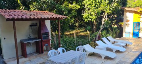 a group of white chairs and a gazebo at Sítio Guaramiranga para 10 pessoas com fácil acesso in Guaramiranga