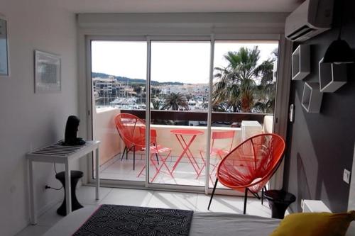 une chambre avec deux chaises, une table et un balcon dans l'établissement Naturiste Cap d'Agde Port Nature 650, au Cap d'Agde