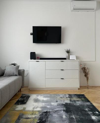 a living room with a white dresser with a tv on a wall at Apartman Noel Knin in Knin