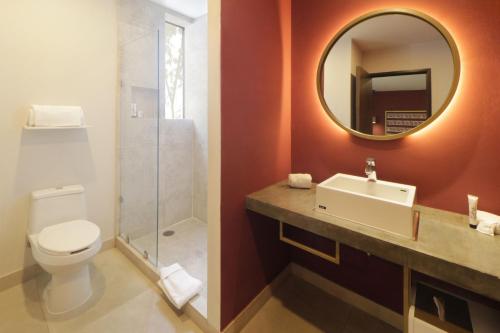 La salle de bains est pourvue de toilettes, d'un lavabo et d'un miroir. dans l'établissement City Centro by Marriott Oaxaca, à Oaxaca
