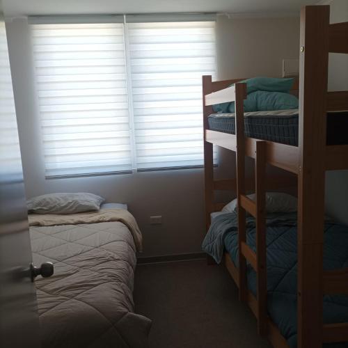 a room with two bunk beds and a window at Amplio y comodo departamento in La Serena