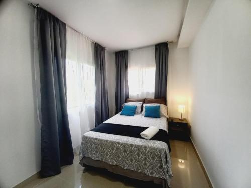 ein kleines Schlafzimmer mit einem Bett mit blauen Kissen in der Unterkunft Villa San Diego in San Pedro Sula