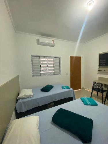 a bedroom with two beds and a desk with a computer at Vaz Lobo Kitnets in Mococa