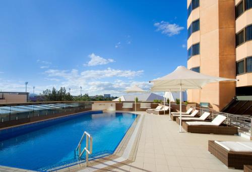 a swimming pool with chairs and an umbrella on a building at InterContinental Adelaide, an IHG Hotel in Adelaide