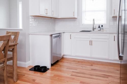 a white kitchen with white cabinets and a wooden floor at Rest in Westerly in Westerly