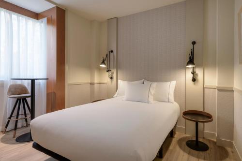 - une chambre avec un grand lit blanc et un tabouret dans l'établissement AC Hotel Los Vascos by Marriott, à Madrid