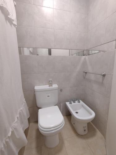 La salle de bains blanche est pourvue de toilettes et d'un lavabo. dans l'établissement Departamento moderno para 2 personas, à Santiago del Estero