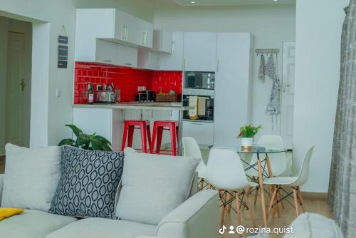 a living room with a couch and a kitchen with red cabinets at Crystal Apartments Area 43 in Lilongwe